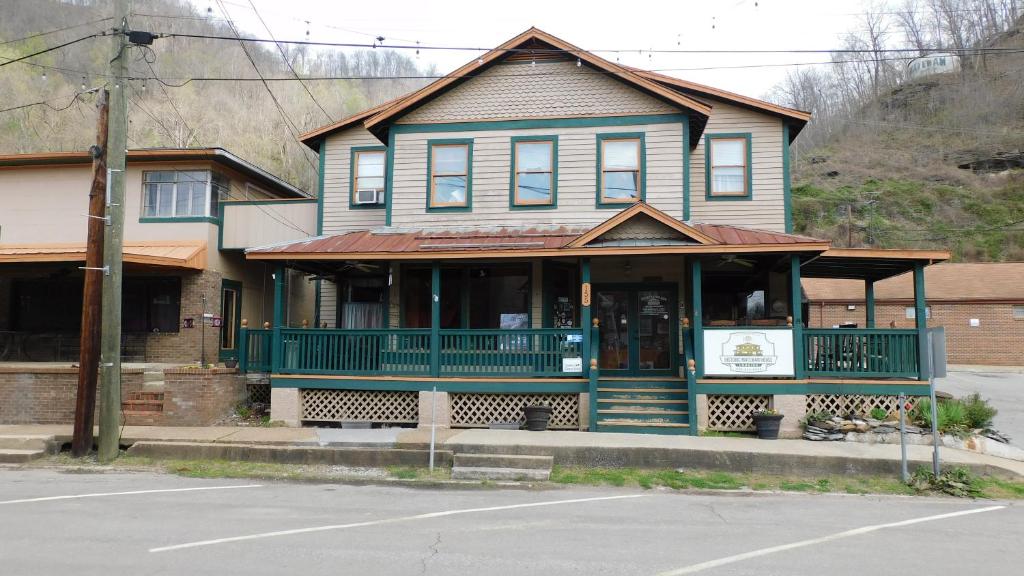 an old house with a green porch and a building at Historic Matewan House Lodging in Matewan