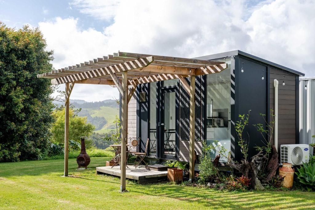a tiny house with a pergola in a yard at Deloraine Tiny Retreat by Tiny Away in Whangarei