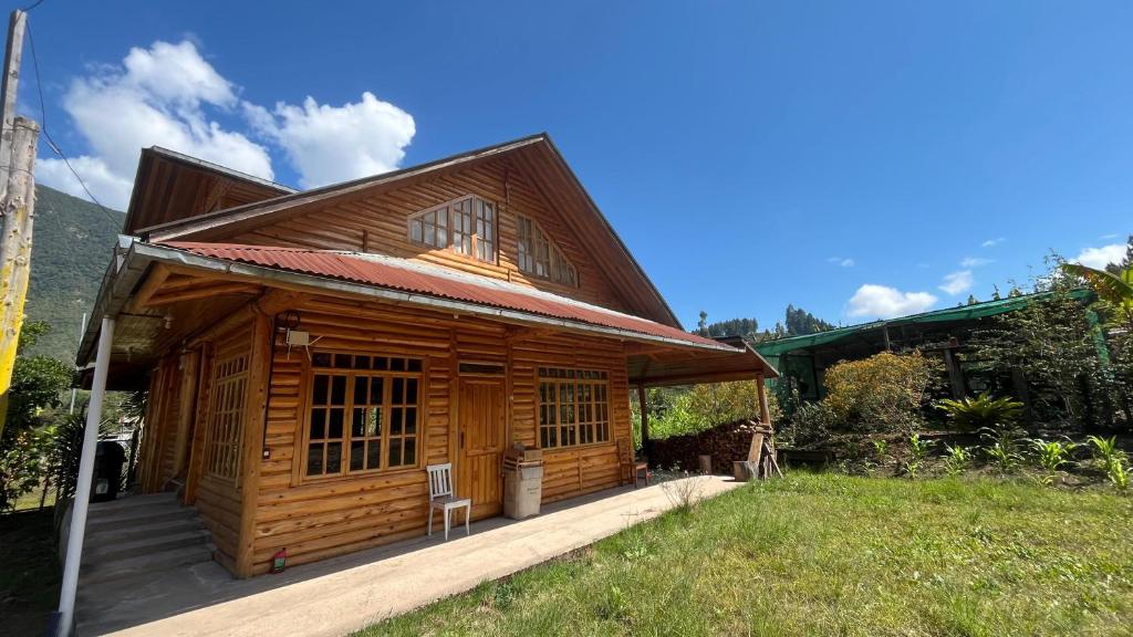 a wooden cabin with a porch in a field at CABAÑA RaNCH OXAPAMPA in Oxapampa