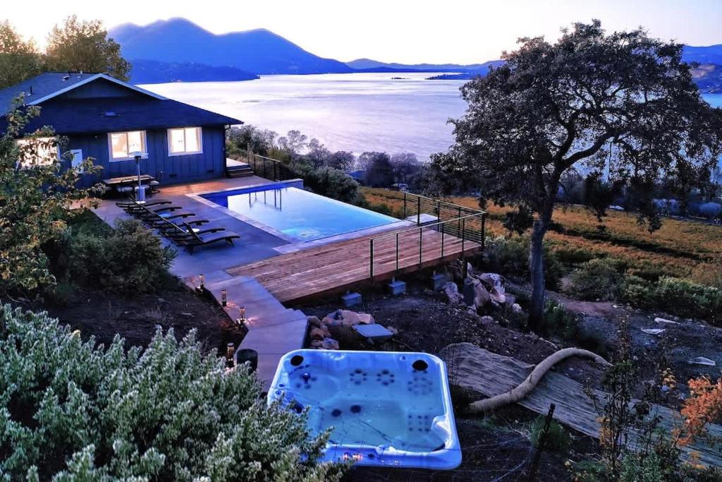 a house with a swimming pool next to a lake at Vineyard Setting With 180 Panoramic Lake Views in Lower Lake