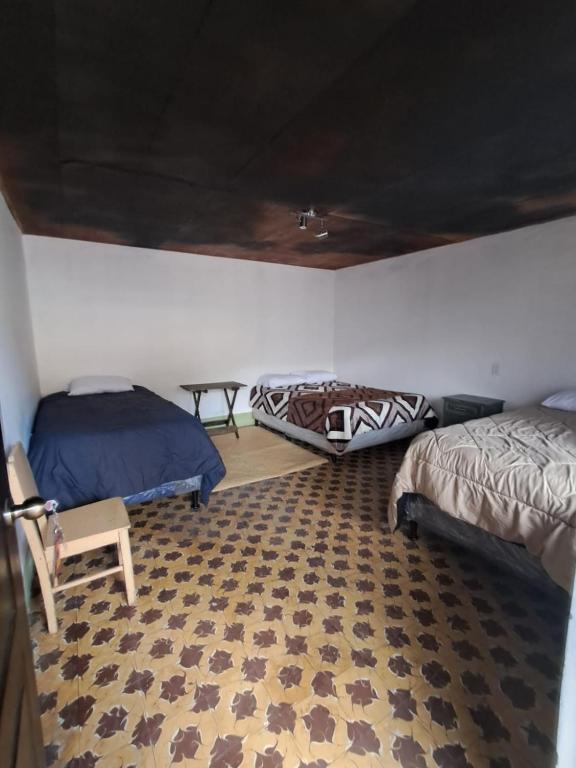a bedroom with two beds and a rug at La Casa del Barrio in Quetzaltenango