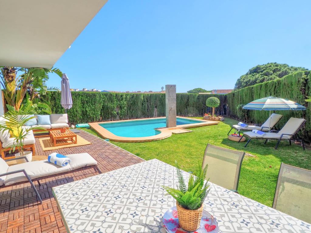a backyard with a pool with chairs and a table at Villa Serena in Mijas Costa
