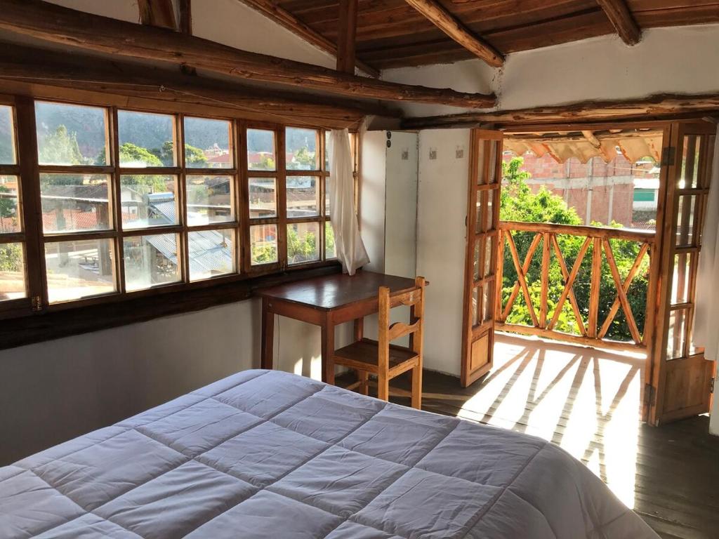 a bedroom with a bed and a desk and windows at Los Laureles Sacred valley in Urubamba