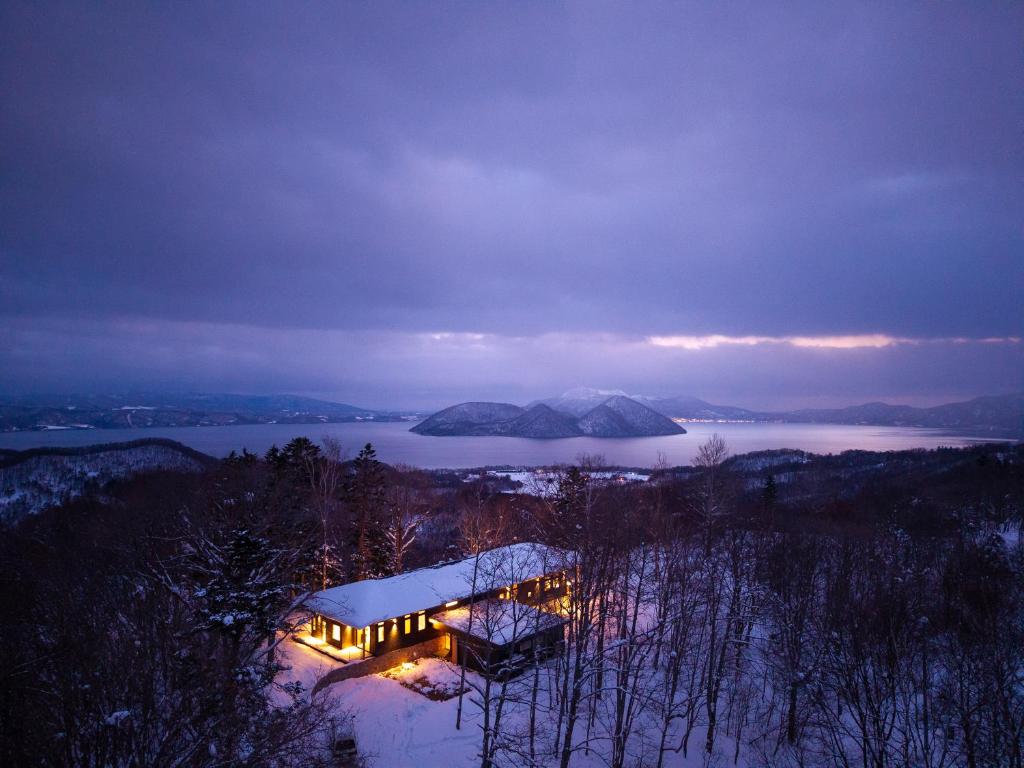 a house on a hill with lights in the snow at Kogetsu To 湖月燈 in Lake Toya