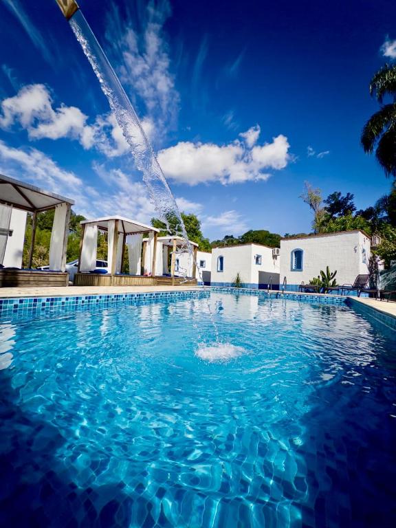 a large swimming pool with a water fountain at Pousada Santorini Guararema in Guararema
