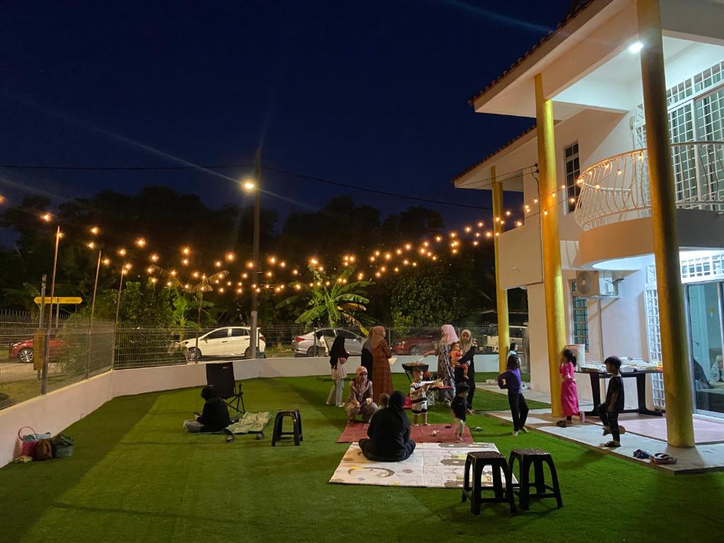 a group of people sitting on the grass outside of a building at Anggun's palace in Pasir Gudang