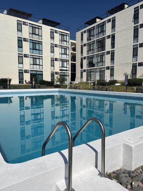 a swimming pool with two apartment buildings in the background at Gran departamento con alberca, terraza y vista a lago en Lago Luna - 5 minutos de Chante Spa in Chantepec