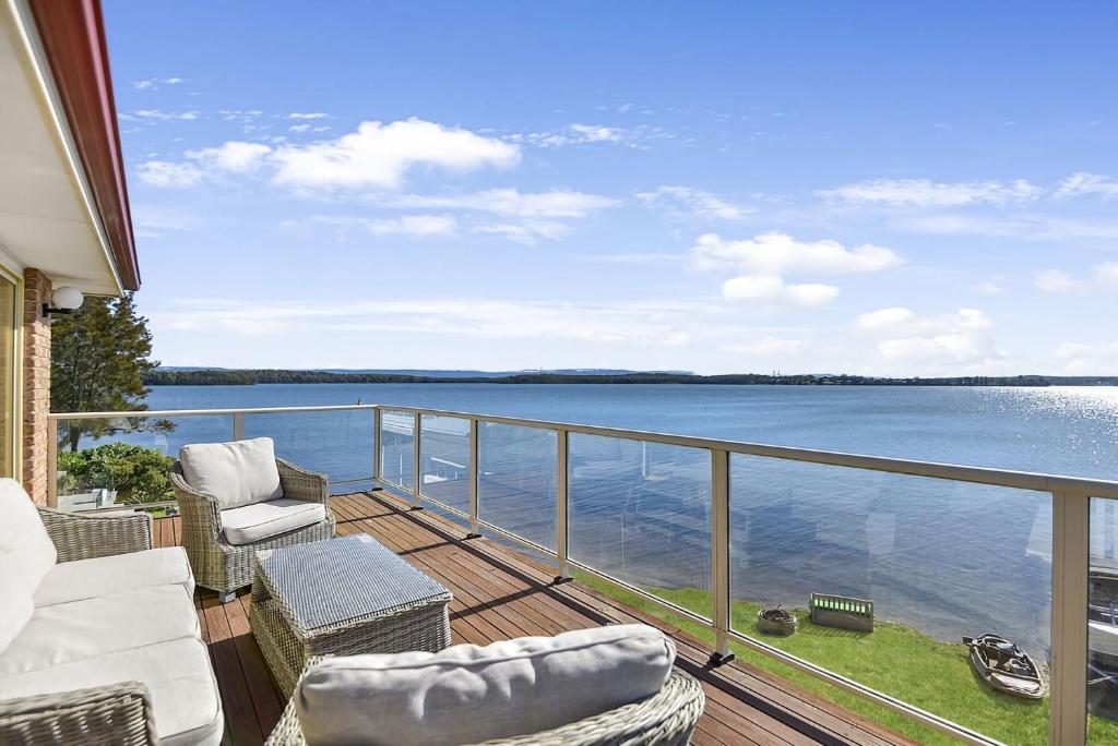 a balcony with chairs and a view of the water at Bluewater at Mannering Park in Mannering Park