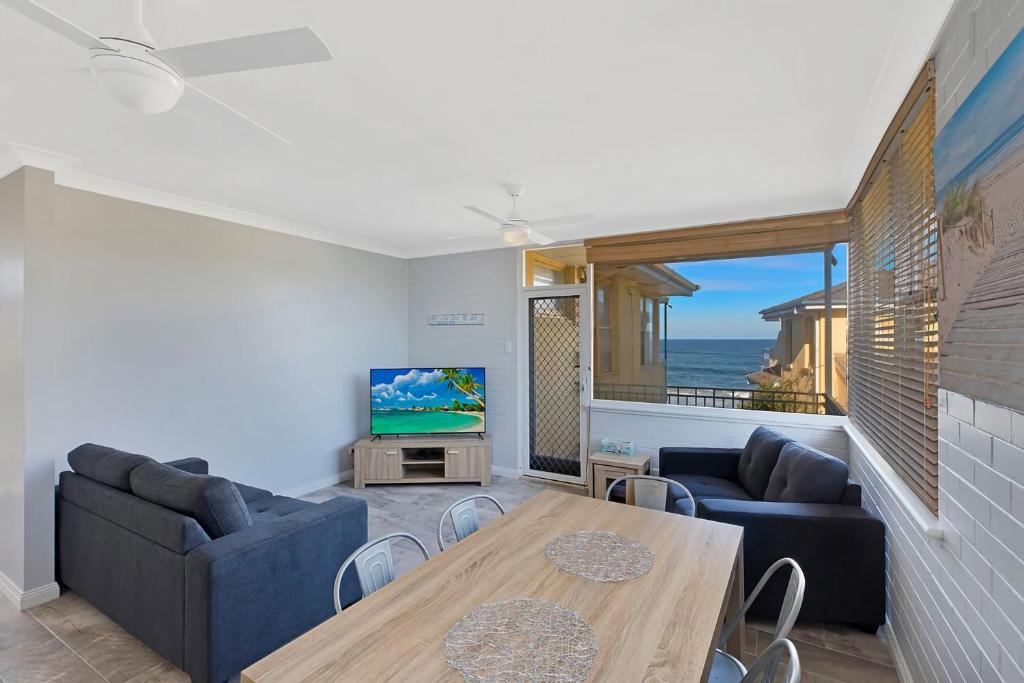 a living room with a couch and a table and a television at Golden Sands Apartment 10 in The Entrance