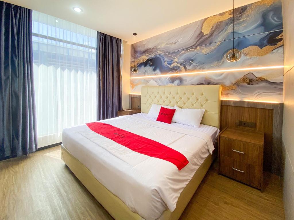 a bedroom with a bed with a painting on the wall at RedDoorz Plus at edOtel Malang in Betek