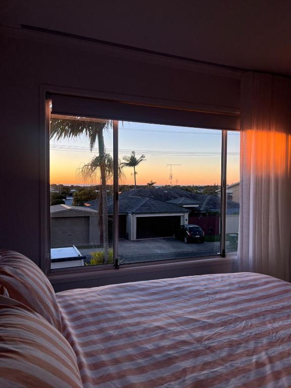 a bedroom with a bed and a large window at The Sage Sea Shack in Caloundra