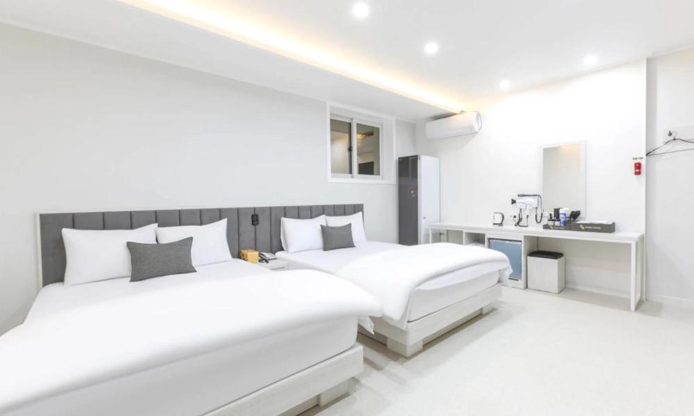 a white bedroom with two beds and a desk at Gimcheon Sweet Hotel in Kimch'ŏn