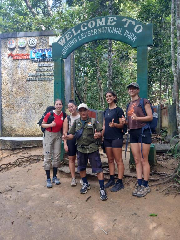 a group of people standing in front of a sign at Orangutan Inn in Bukit Lawang