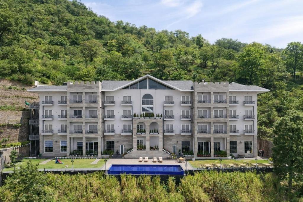 an exterior view of a large white building with trees at The Belvedere Kasauli in Kasauli