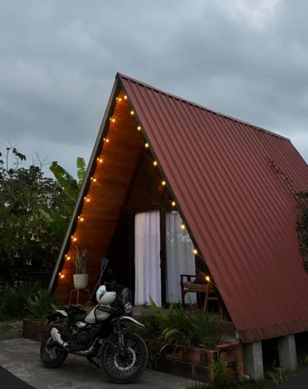 a motorcycle parked in front of a house with lights at Glamping Encanto Amazónico Macas in General Proaño