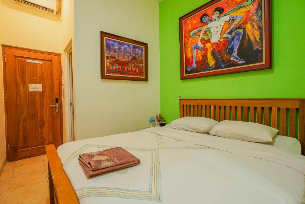 a green bedroom with a bed and a painting on the wall at The Cabin Hotel Mantrijeron in Yogyakarta