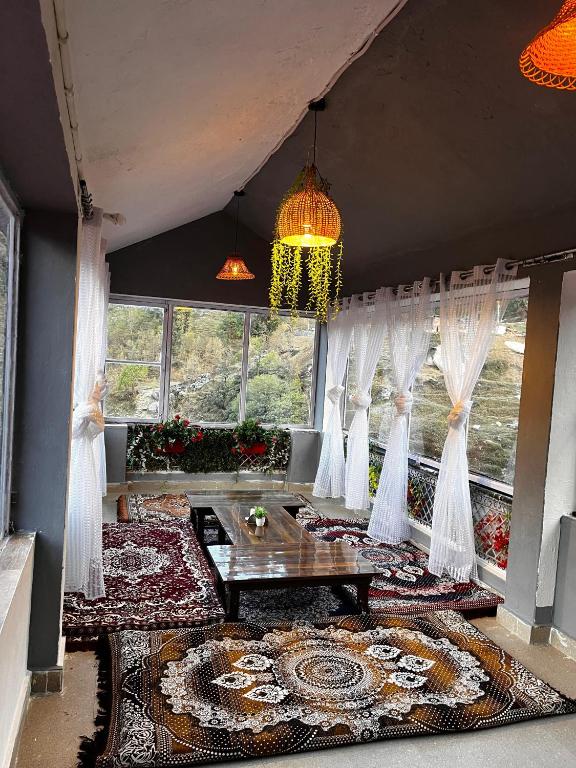 a living room with white curtains and a chandelier at Mayadeep Resort and Hostels in Chopta