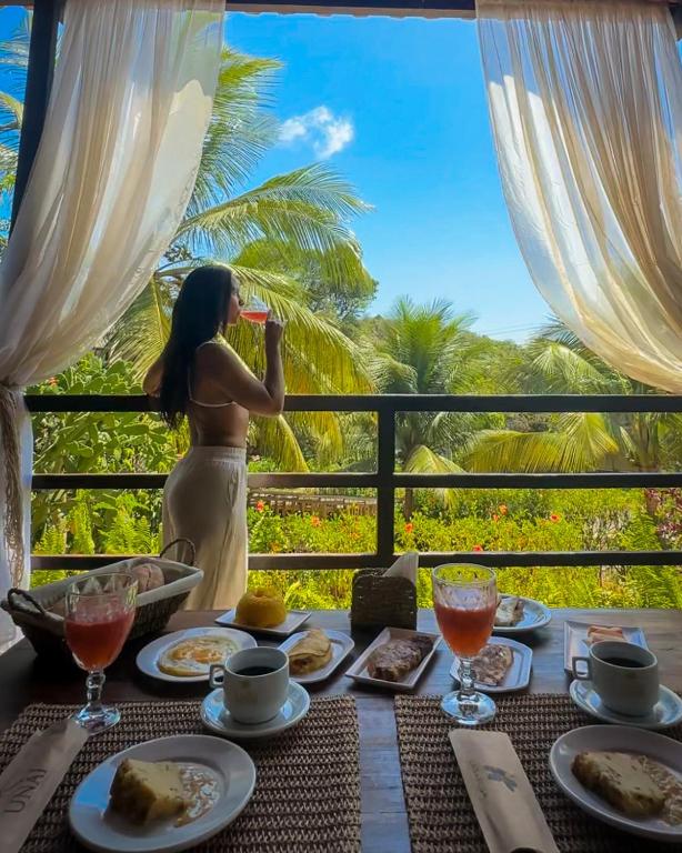 a woman standing on a balcony drinking a glass of wine at Pousada Unaí - Casa Flor in Fernando de Noronha