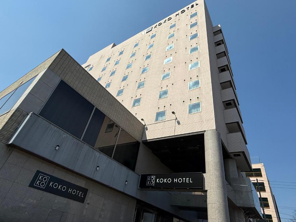 a building with a sign in front of it at KOKO HOTEL Tomakomai in Tomakomai