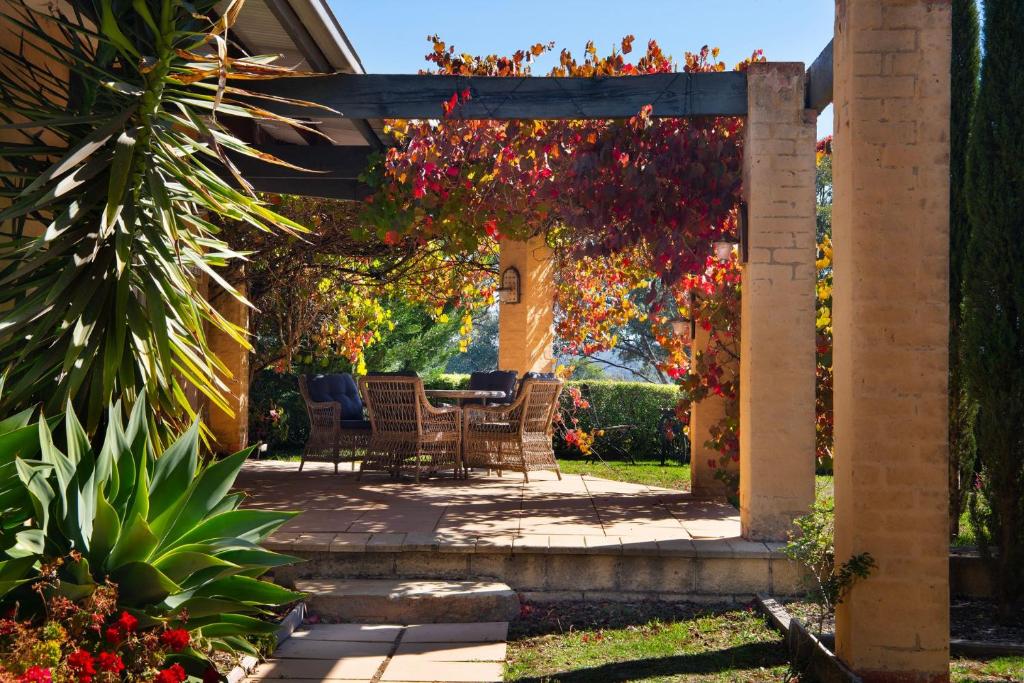 a patio with a table and chairs under a pergola at El Camino in Hepburn Springs