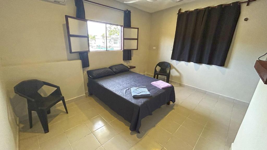 ein Schlafzimmer mit einem Bett, einem Stuhl und einem Fenster in der Unterkunft Luz Sofia Bacalar in Bacalar