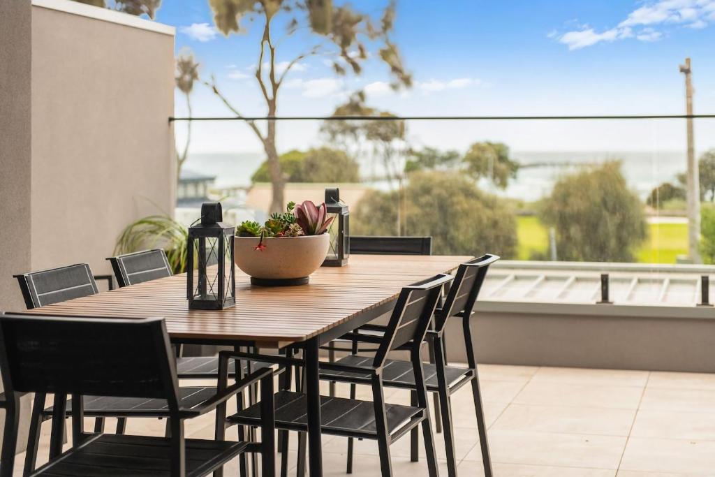 a wooden table and chairs on a balcony at Beachfront Bliss Luxury Views in Rye