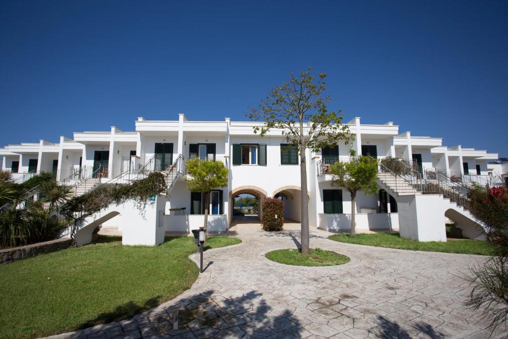 ein großes weißes Gebäude mit Treppen und Gras in der Unterkunft Hotel Resort Portoselvaggio in Sant'Isidoro