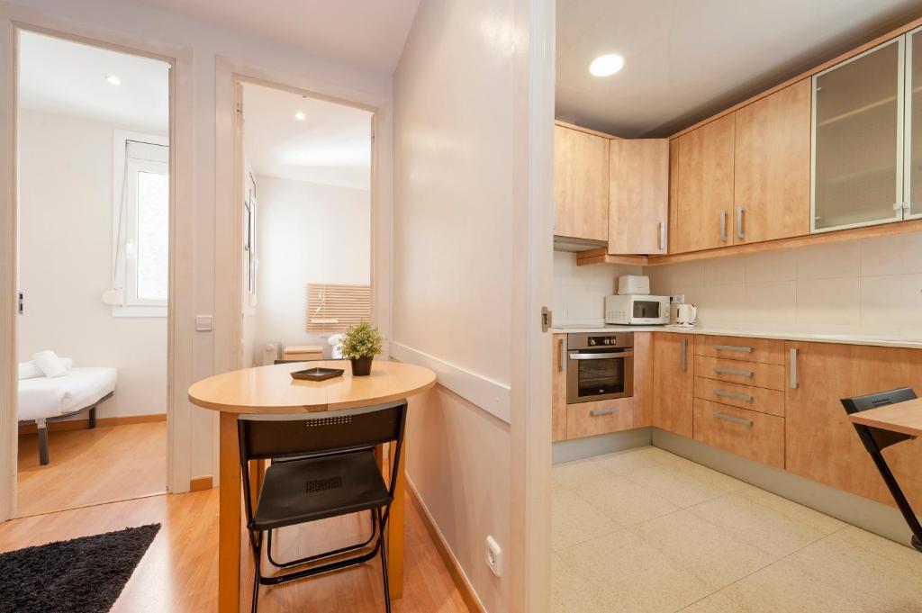 a kitchen with wooden cabinets and a small table at Bbarcelona Apartments Plaza España Flats in Barcelona