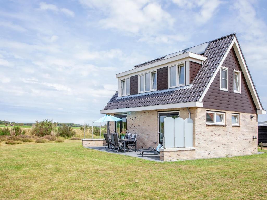a brick house with a table and chairs on a lawn at Stylish Texel Escape with Spa in Den Burg