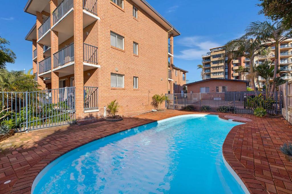 a swimming pool in front of a apartment building at Surfside Palms 14 in The Entrance