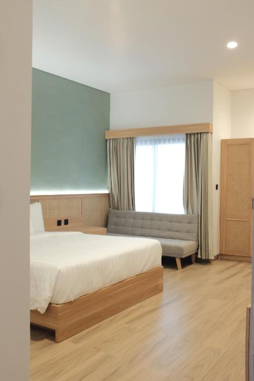 a bedroom with a bed and a couch and a window at Griya Yunika in Yogyakarta