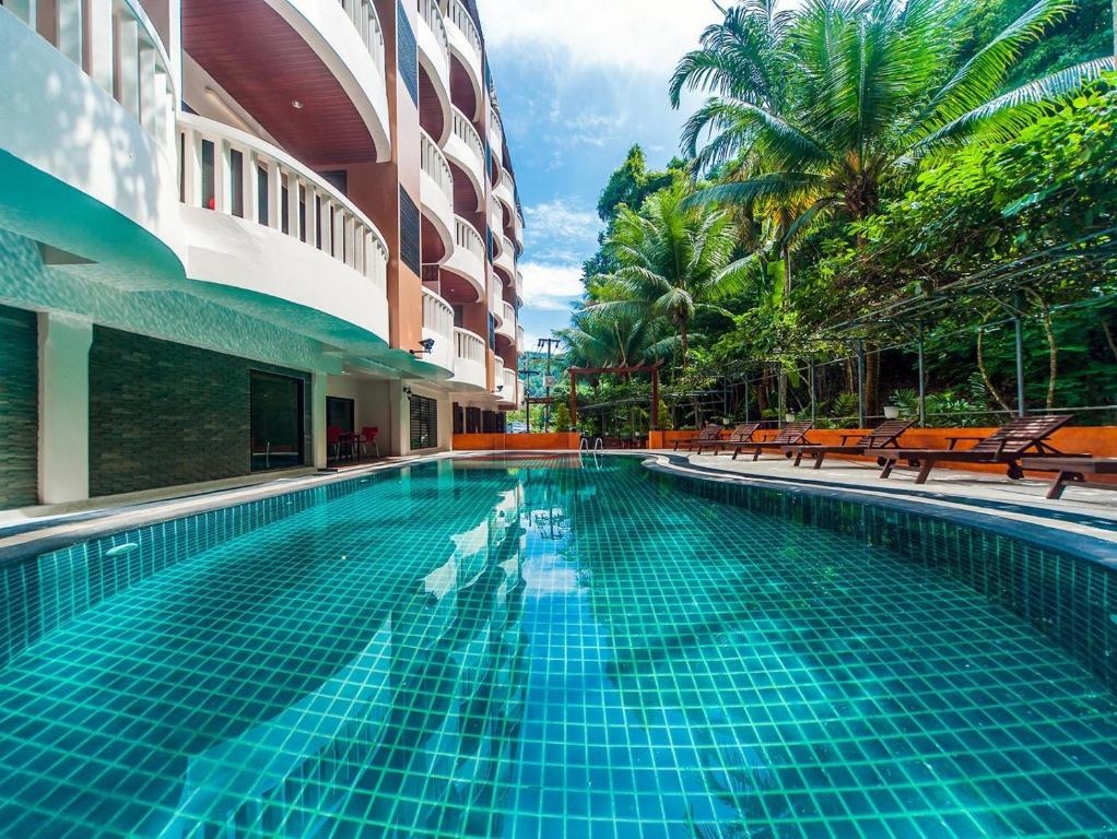 a swimming pool in a building with benches and palm trees at Ratana Hill Patong in Patong Beach