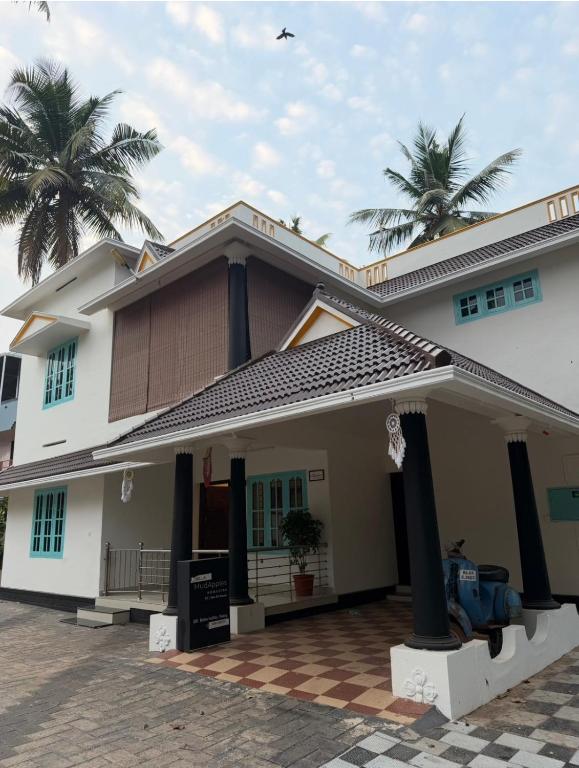 a house with palm trees in the background at Villa mud apples varkala in Varkala