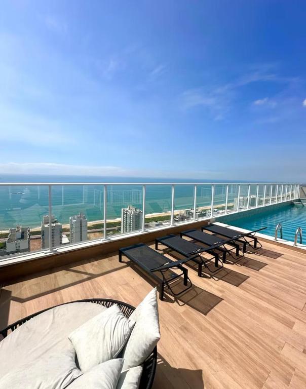 a balcony with benches and a view of the ocean at Apartamento Novo Infinity in Vila Velha