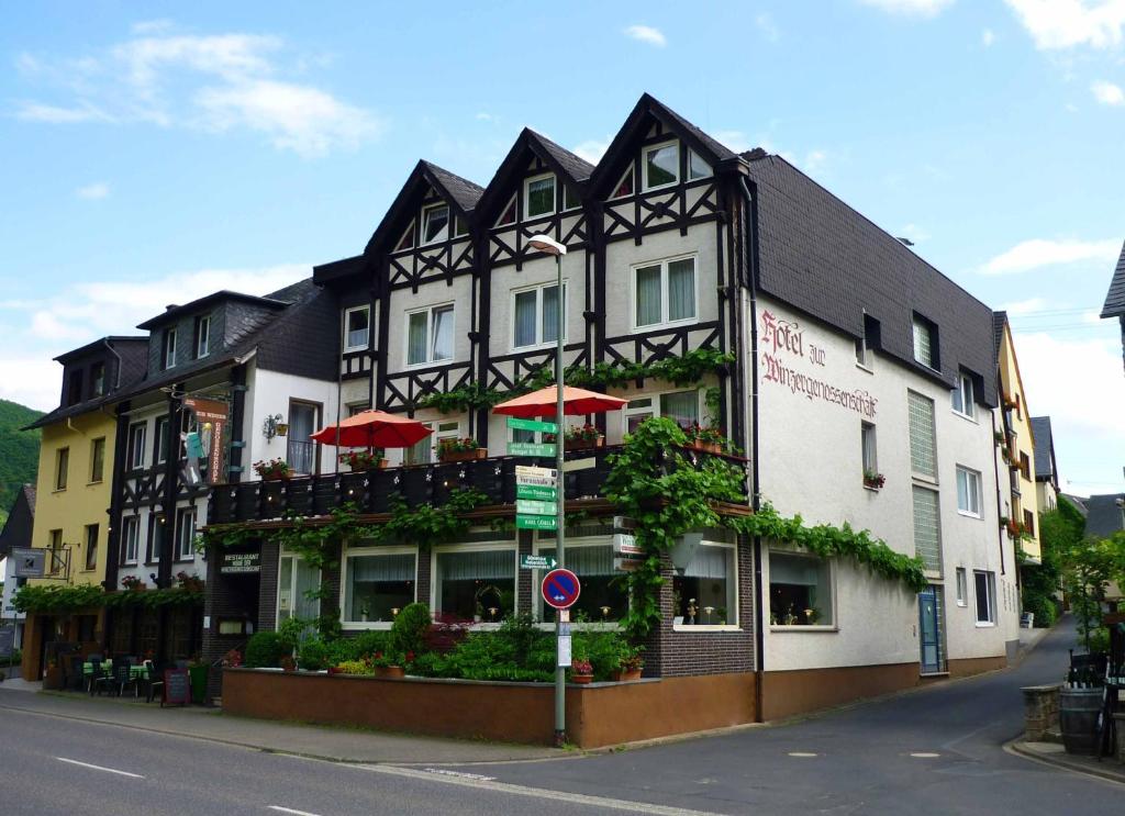 Hotel zur Winzergenossenschaft في ارنست: مبنى اسود وبيض مع مظلات حمراء على شارع