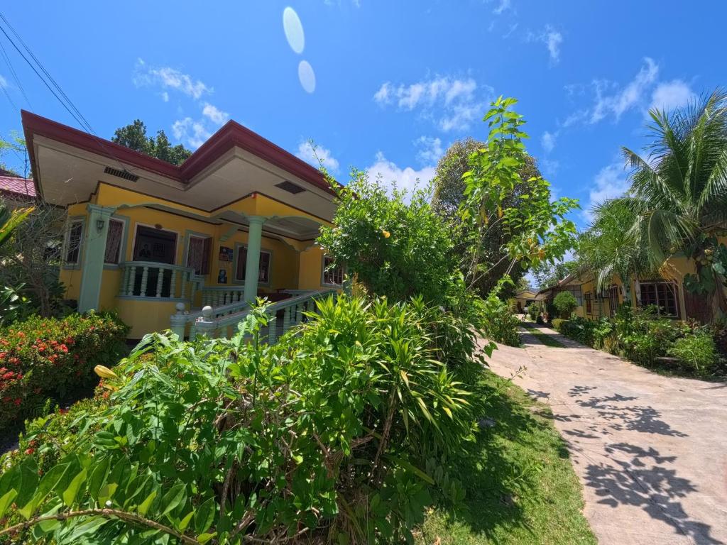 a yellow house on the side of a dirt road at Xylla Guesthouse in Ytaya