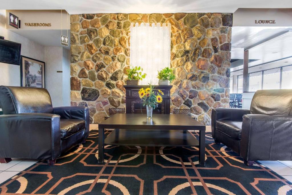 a lobby with leather chairs and a table and a stone wall at Econo Lodge in Sudbury