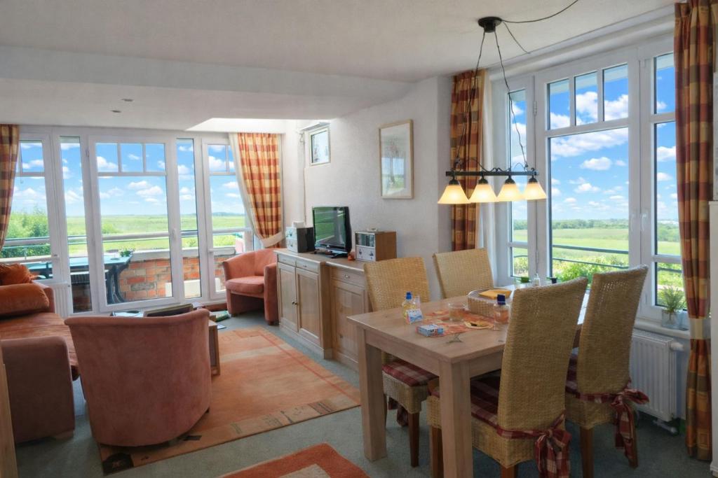 a living room with a dining room table and chairs at Meerblick aus allen Räumen - de Tampen in Dorum-Neufeld