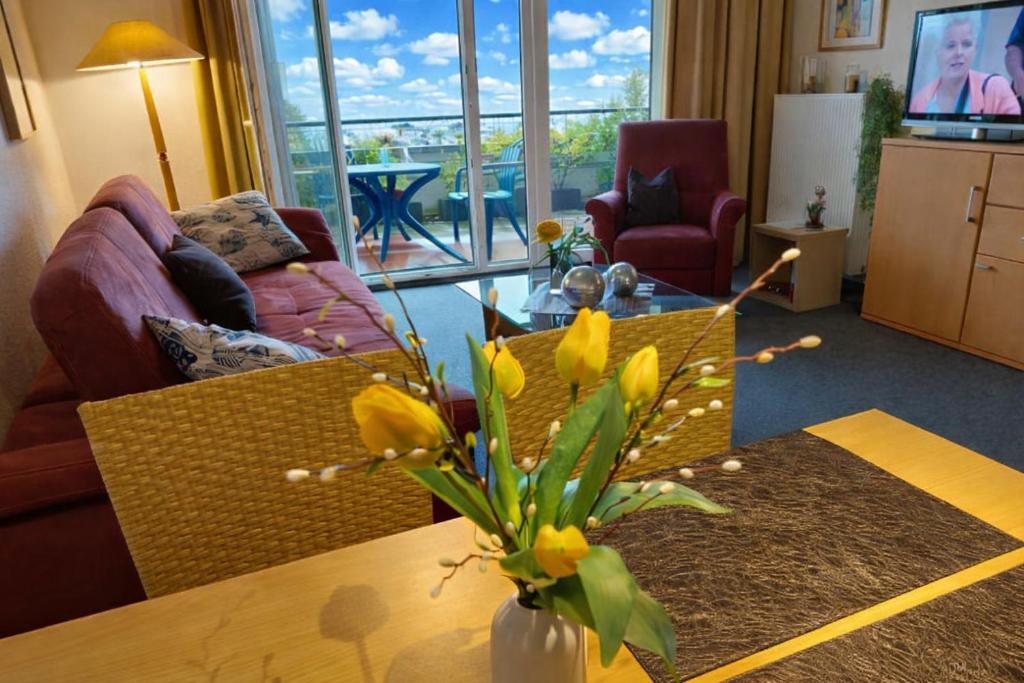 a living room with a couch and a table with flowers at de Leuchtviol in Dorum-Neufeld