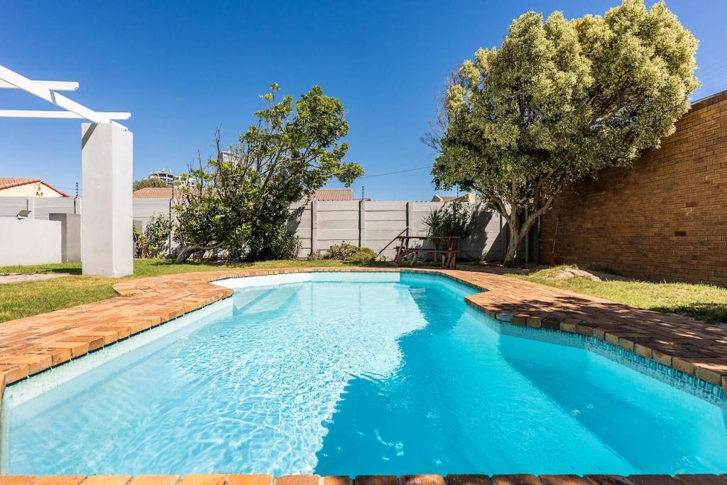 a swimming pool in a yard with a brick wall at The Sands Cottage in Cape Town