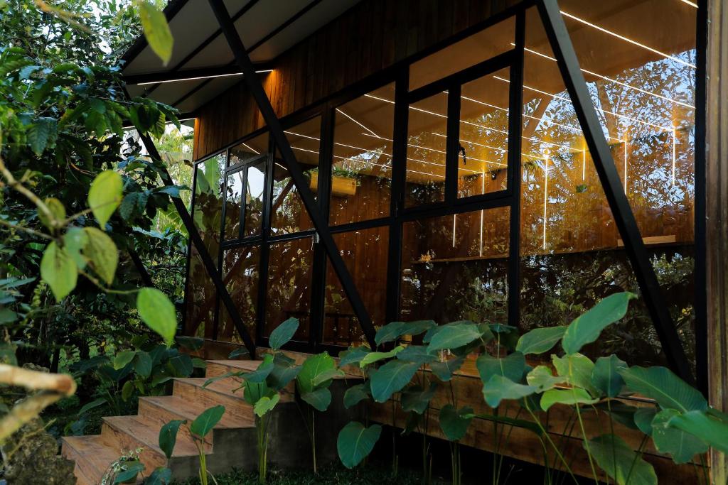 a wooden house with glass windows and plants at HoneyStone Resort in Sultan Bathery