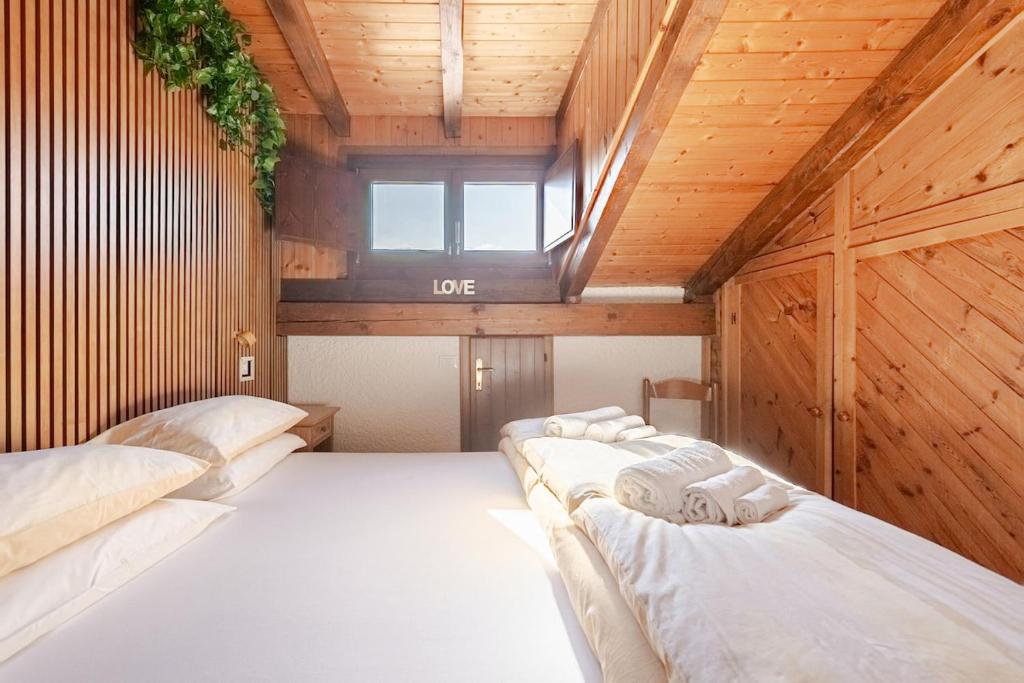 two beds in a room with wooden walls and a window at Val di Sole Apartment in Monclassico