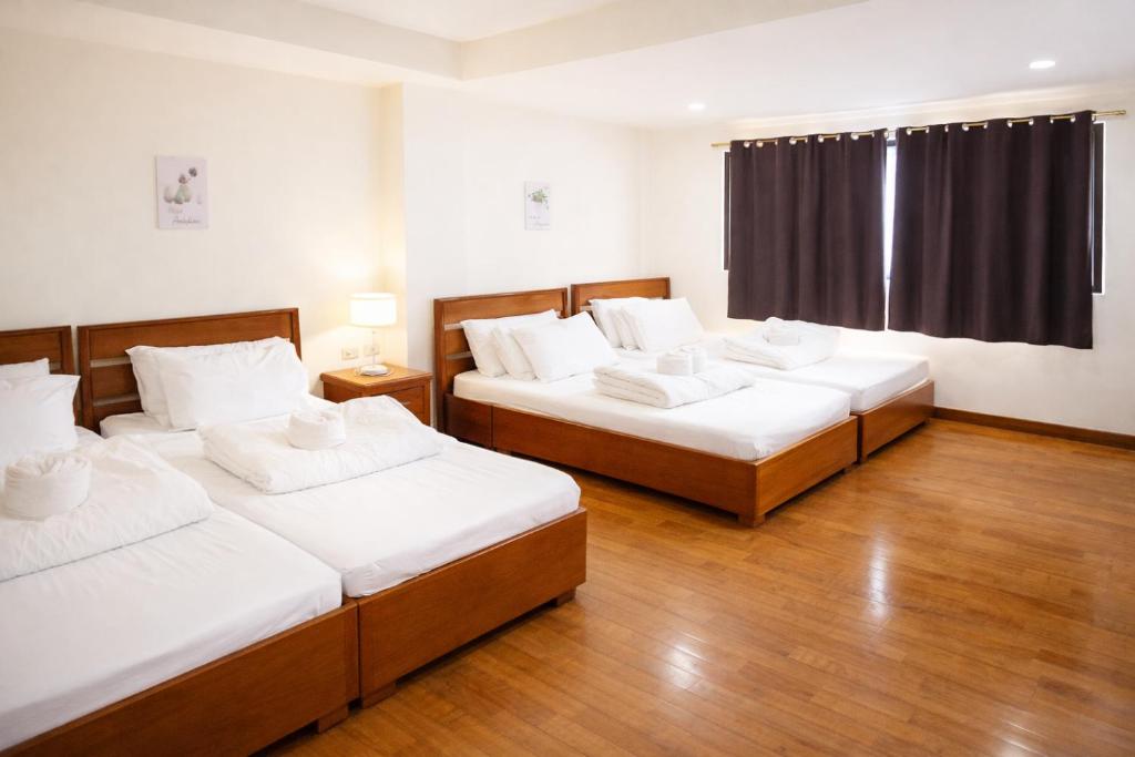 three beds in a room with wood floors and a window at Zhongkebole Suites in Baguio