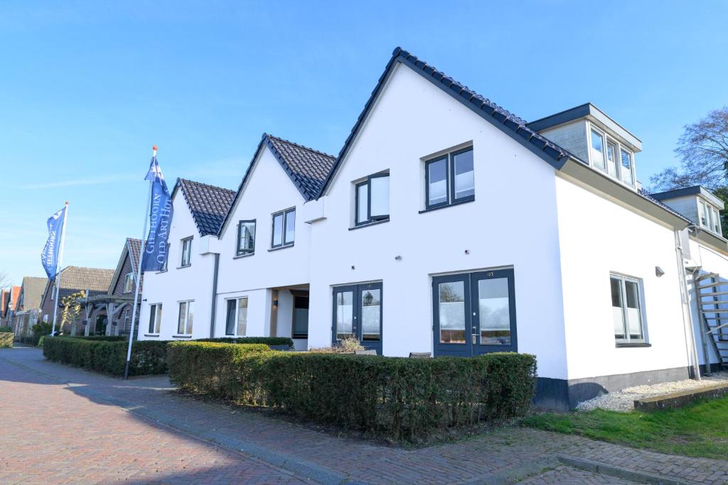 a white building with black windows on a street at Giethoorn Old Art Hotel in Giethoorn