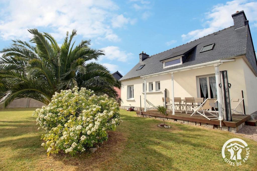 a white house with a palm tree and a deck at Le palmier in Penvénan