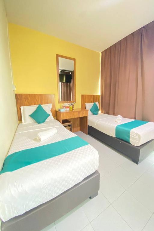 a bedroom with two beds and a mirror at Sun Tree Hotel at Triang in Kampong Kerayong