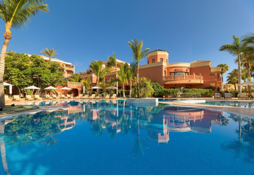 a swimming pool in front of a resort with palm trees at Hotel Las Madrigueras Golf Resort & Spa - Adults Only in Playa de las Americas