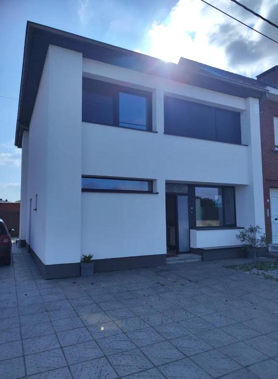 a white facade of a house with the sun shining on it at Casa 28 in Kapelle-op-den-Bos