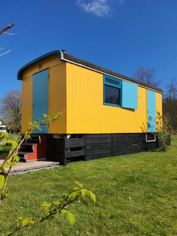 a yellow and blue house on a grass field at De Maanloper in Bant
