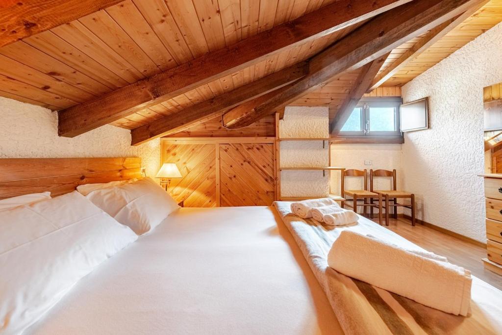 a bedroom with a large white bed and wooden ceilings at Rifugio del Sole Apartment in Monclassico